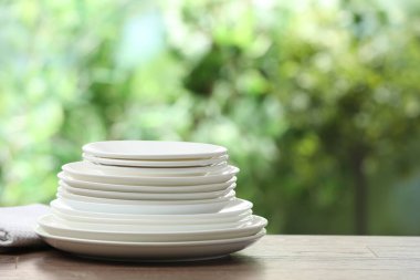 Clean dishware on wooden table against blurred background. Space for text