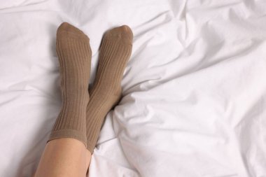 Yatakta açık kahverengi çoraplar giyen bir kadın. Metin için boşluk