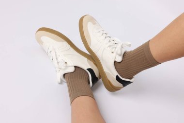 Açık kahverengi çorap giyen ve beyaz arka planda şık ayakkabılar giyen kadın, yakın plan.