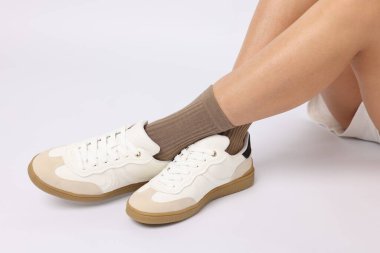 Açık kahverengi çorap giyen ve beyaz arka planda şık ayakkabılar giyen kadın, yakın plan.