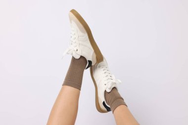 Açık kahverengi çorap giyen ve beyaz arka planda şık ayakkabılar giyen kadın, yakın plan.