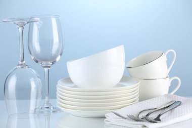 Different clean dishware on light blue background
