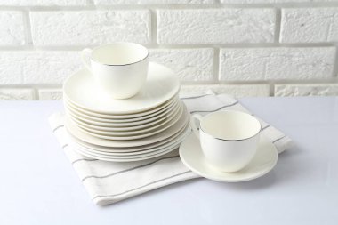 Different clean dishware on white table near brick wall