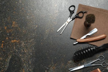 Many different barber's tools on black textured table, flat lay. Space for text