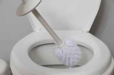 Cleaning toilet bowl with brush indoors, closeup