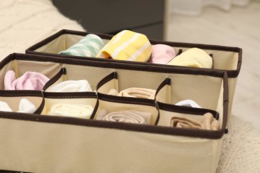 Organizers with folded clothes on bed indoors, closeup