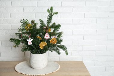 Beautiful Christmas composition of decorated fir tree branches on wooden table near white brick wall, space for text