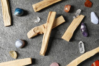 Palo santo sticks and gemstones on grey table, flat lay
