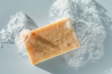 Grimsi mavi arkaplanda köpüklü sabun çubuğu, üst görünüm