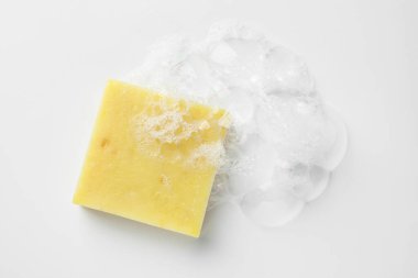 Beyaz arka planda köpük olan sabun çubuğu, üst görünüm