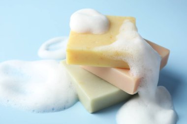 Açık mavi arka planda köpüklü sabun çubukları, yakın plan