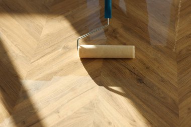 Polishing parquet with roller and varnish indoors, closeup. Space for text