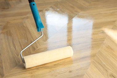 Polishing parquet with roller and varnish indoors, closeup. Space for text