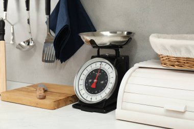 Retro mechanical kitchen scale and other utensils on white countertop indoors