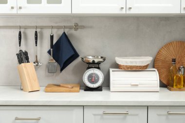 Retro mechanical kitchen scale and other utensils on white countertop indoors