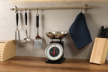 Retro mechanical kitchen scale on wooden countertop and other utensils indoors