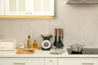 Retro mechanical kitchen scale and other utensils on white marble countertop indoors
