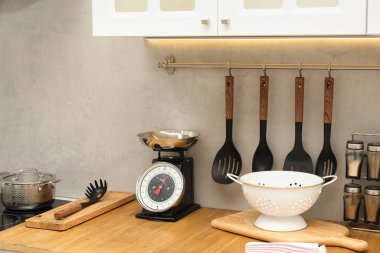Retro mechanical kitchen scale and other utensils on wooden countertop indoors