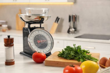 Retro mekanik mutfak ölçeği ve beyaz mermer tezgahta farklı gıda ürünleri.