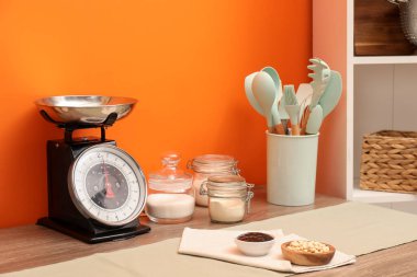 Kitchen scale, products and cooking utensils on wooden table