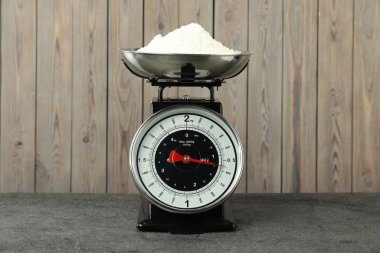 Retro mechanical kitchen scale with flour on grey table