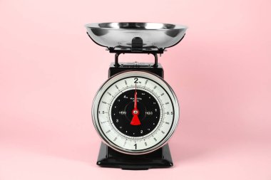One mechanical kitchen scale on pink background