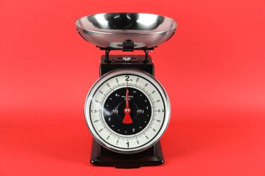 Mechanical kitchen scale with bowl on red background