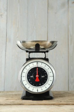 Mechanical kitchen scale with bowl on wooden table