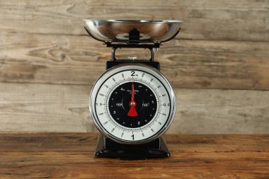 Mechanical kitchen scale with bowl on wooden table