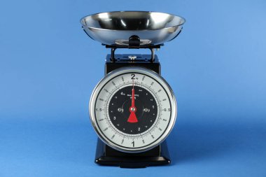 Mechanical kitchen scale with bowl on blue background