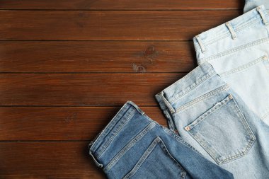 Stylish jeans on wooden background, flat lay. Space for text