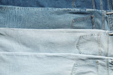 Different stylish jeans as background, top view