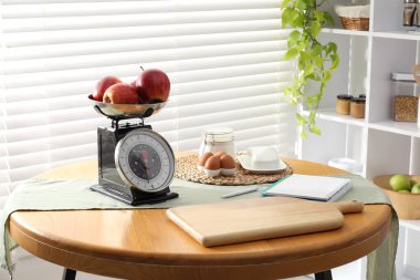 Retro mekanik mutfak ölçeği, ürünler ve ahşap masa üzerindeki kırtasiye.