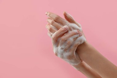 Pembe arka planda köpüklü sabunla ellerini yıkayan bir kadın, mesaj için yeri olan bir kadın. Hijyen