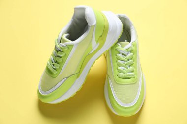 Green sneakers on yellow background, above view. Sportive shoes