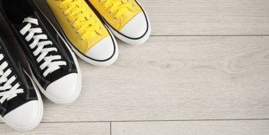 Sportive shoes. Different sneakers on wooden background, flat lay. Space for text