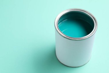 Can of bright paint on turquoise background, space for text