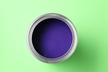 Can of violet paint on light green background, top view
