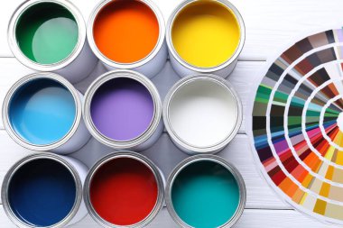 Parlak boya kutuları ve beyaz ahşap masa üzerinde renk paletleri, düz yatıyordu.