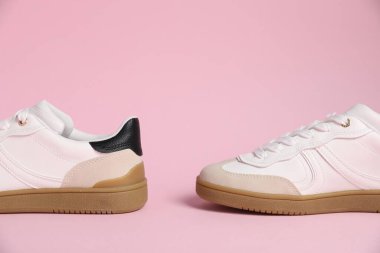 Pair of stylish sneakers on pale pink background, closeup. Casual shoes