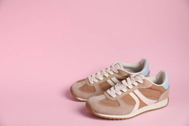 Pair of stylish sneakers on pale pink background, space for text. Casual shoes