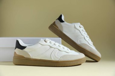 Bir çift şık spor ayakkabı ve soluk zeytinli arka planda bir kutu. Sıradan ayakkabılar.