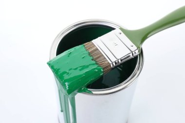 Can of green paint and brush on white background