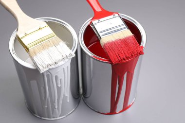 Cans of paint and brushes on grey background, closeup