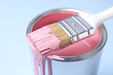 Can of pink paint and brush on light background, closeup