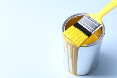 Can of yellow paint and brush on light background. Space for text