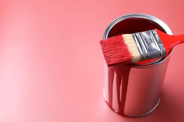 Can of red paint and brush on color background, closeup. Space for text