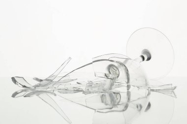 Pieces of broken wine glass on table against white background, closeup