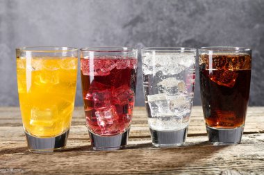 Farklı aromalı soda ve tahta masada buzlu bardaklar.