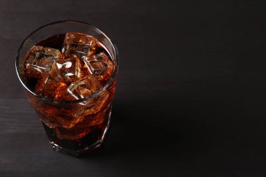 Siyah ahşap masadaki buzlu kolayı tazeliyorum. Yakın plan. Metin için boşluk